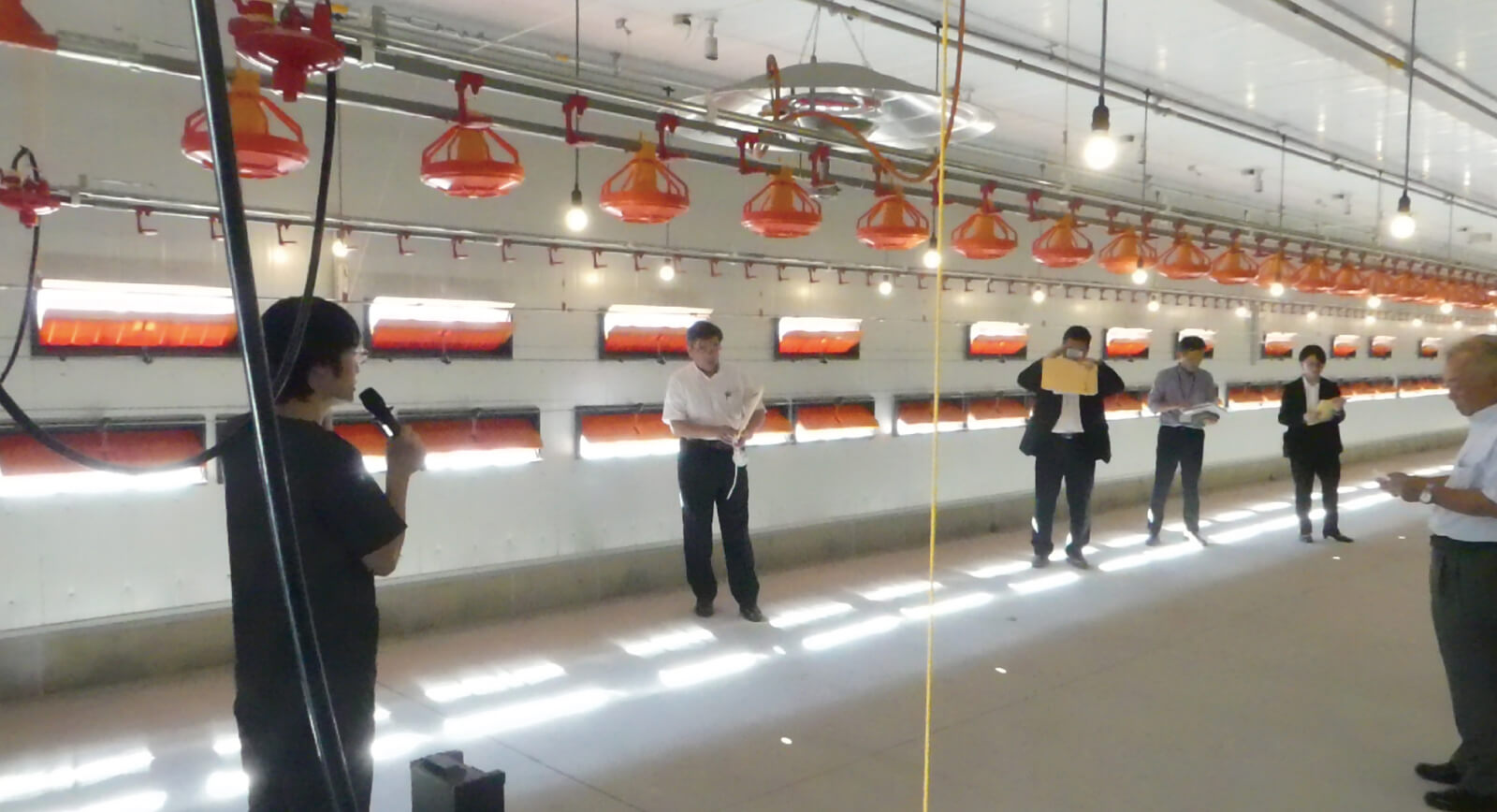 飼養環境を自動制御するウィンドウレスの次世代平飼いモデル鶏舎。バイオセキュリティとアニマルウェルフェアを向上させる設備や、鶏の体重推計や活動量解析を行うための天井設置の監視カメラが設置される